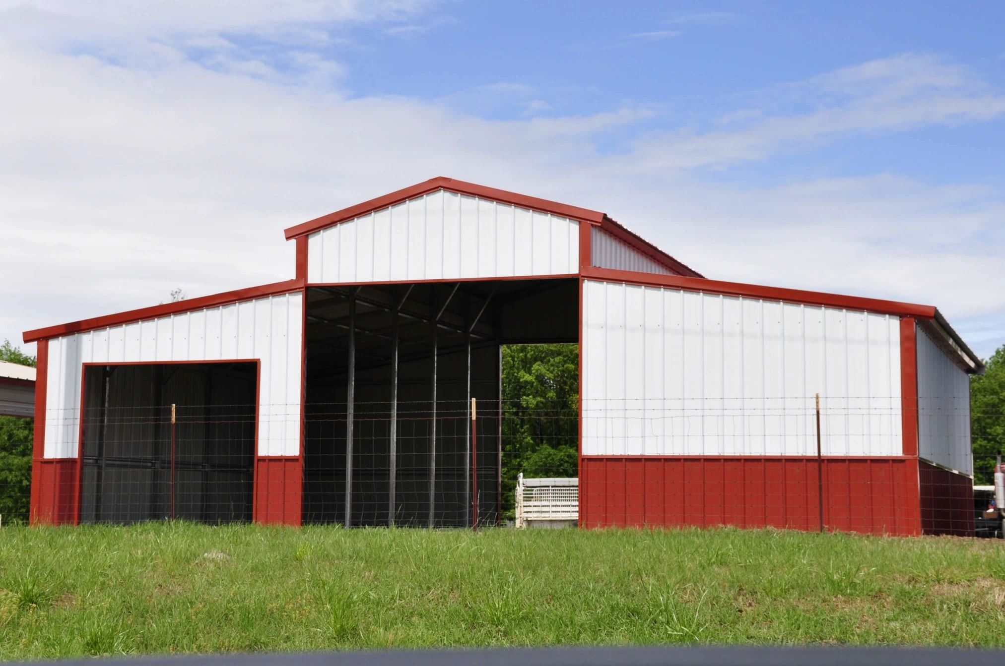 Red metal barn construction under blue sky